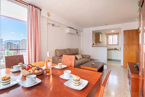 Un salon moderne avec une table à manger pour deux personnes, un canapé et une vue sur la ville.