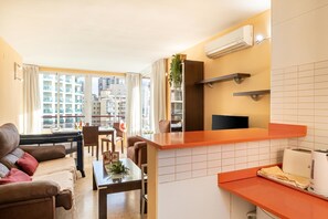 A compact living space with a kitchenette, dining area, and a view of a cityscape.