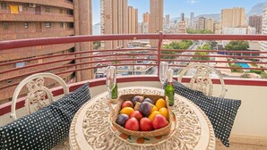 A balcony with a table set with a fruit basket, two wine glasses, and two bottles. - Benidorm Levante Beach 9A, Benidorm, Spain (Benidorm)