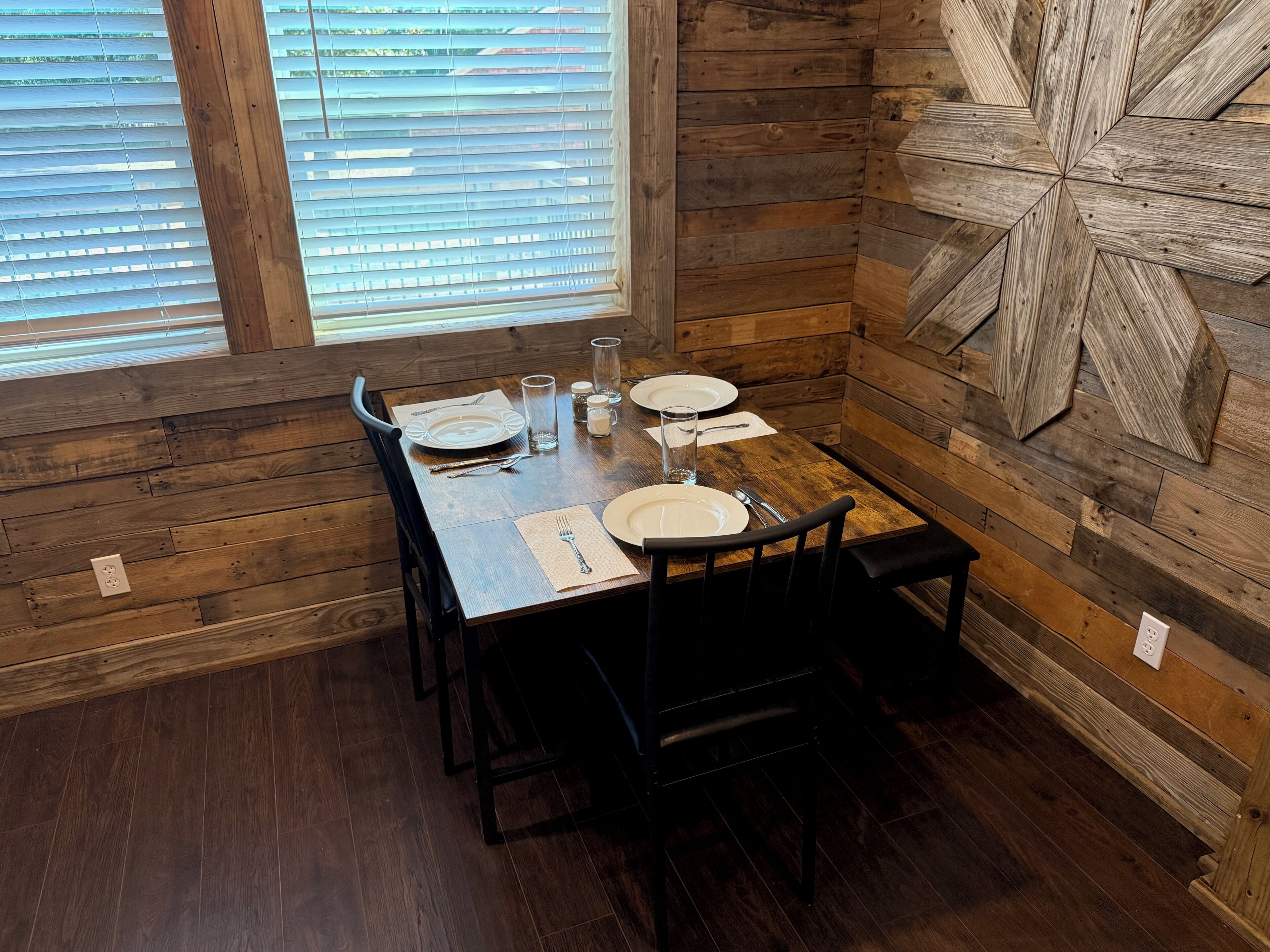 A dining area with a wooden table set for four, including plates, cutlery, and glasses.