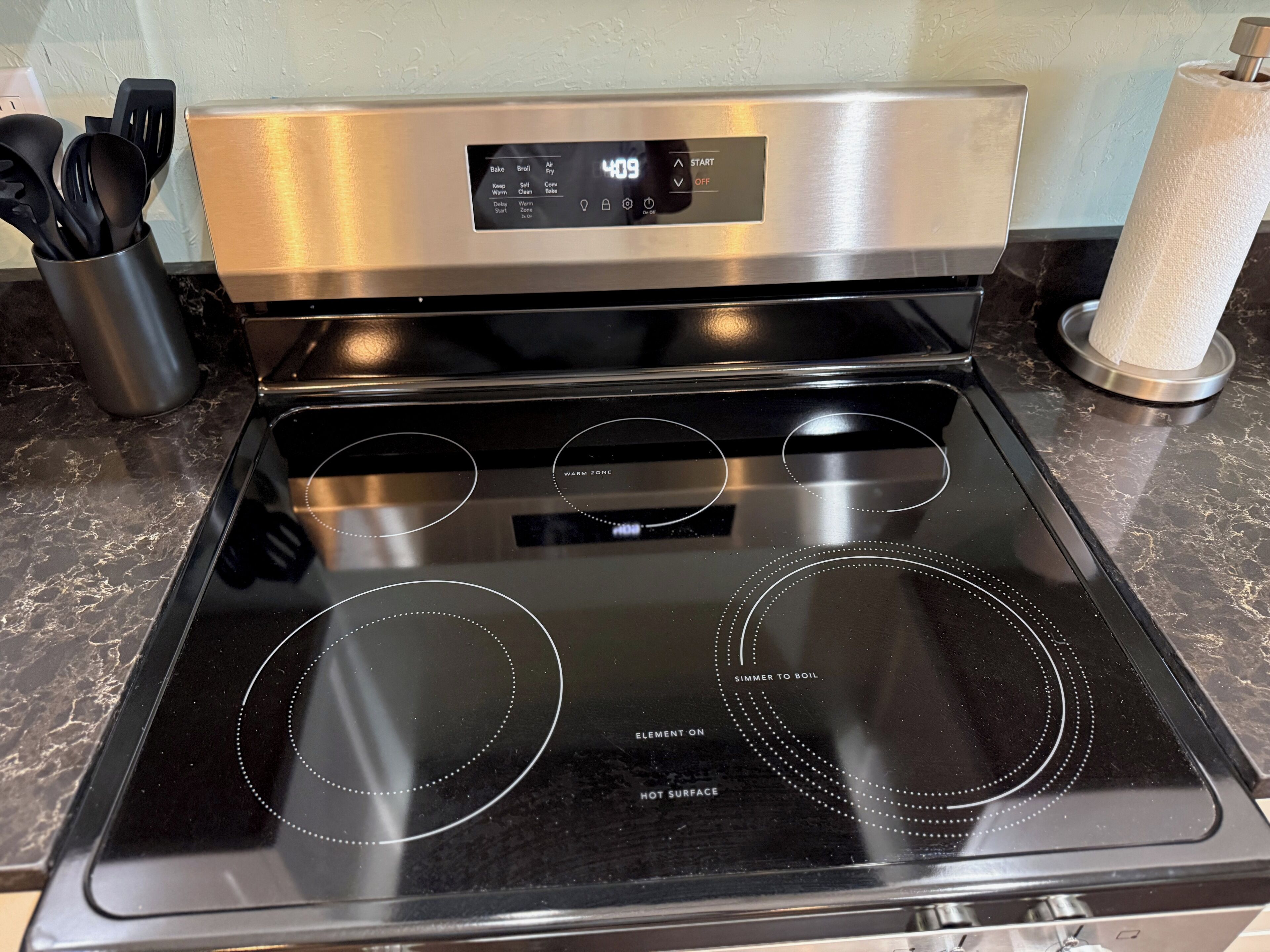 A kitchen with a stainless steel oven and a black stovetop.