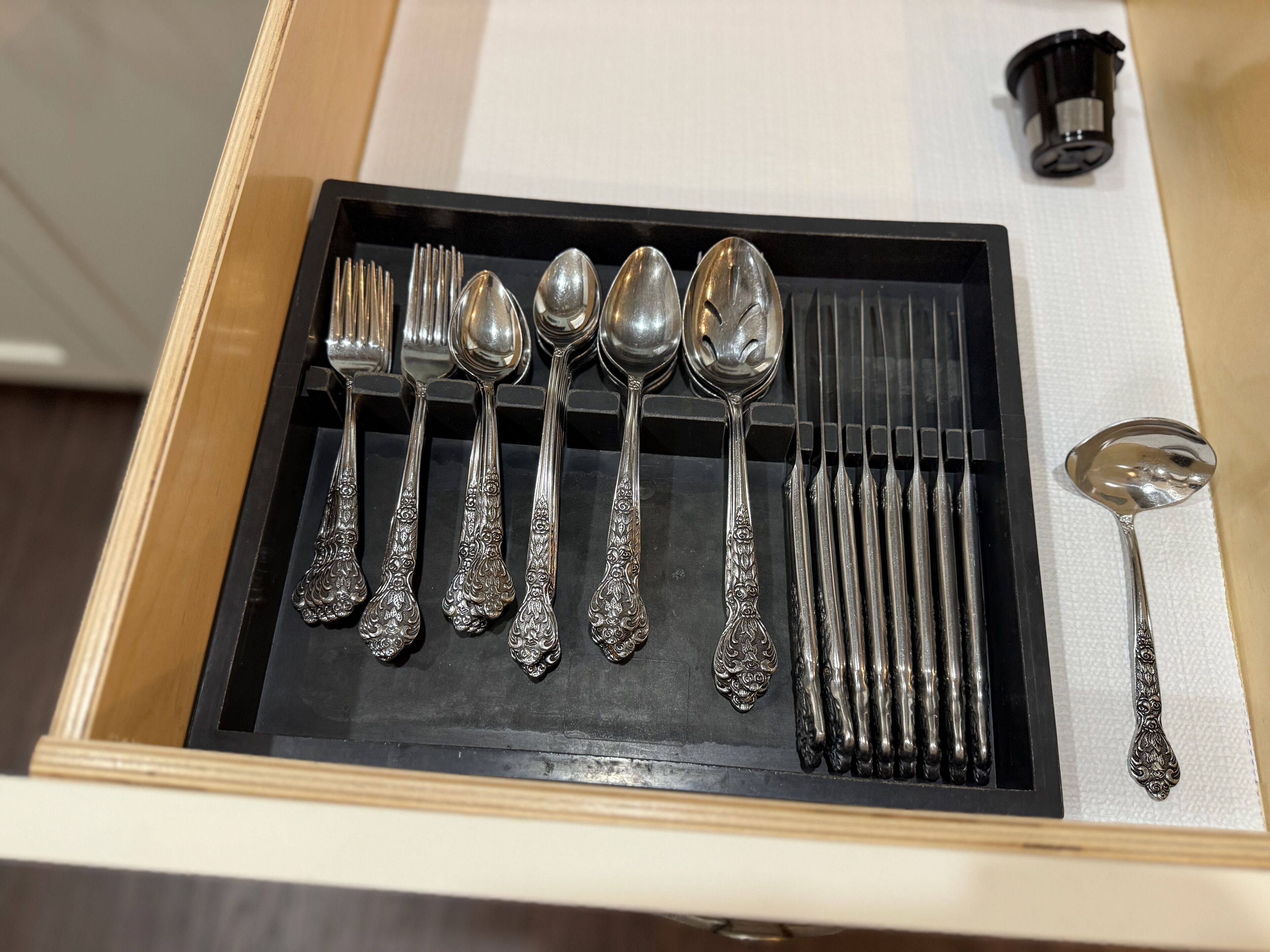 A drawer containing a set of silverware including forks, spoons, and a knife.