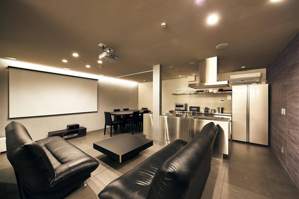 A modern living room with a flat-screen TV, leather sofas, a coffee table, and a dining area with chairs and a table.