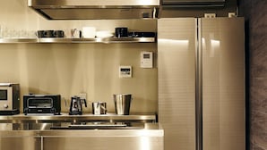 A modern kitchen with stainless steel appliances, including a refrigerator, microwave, and toaster. - MUSASHI Condo Shinjuku (Tokyo)