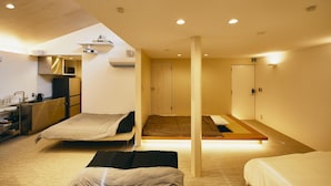 A modern hotel room with a kitchenette, two beds, and a large window. - MUSASHI Condo Shinjuku (Tokyo)