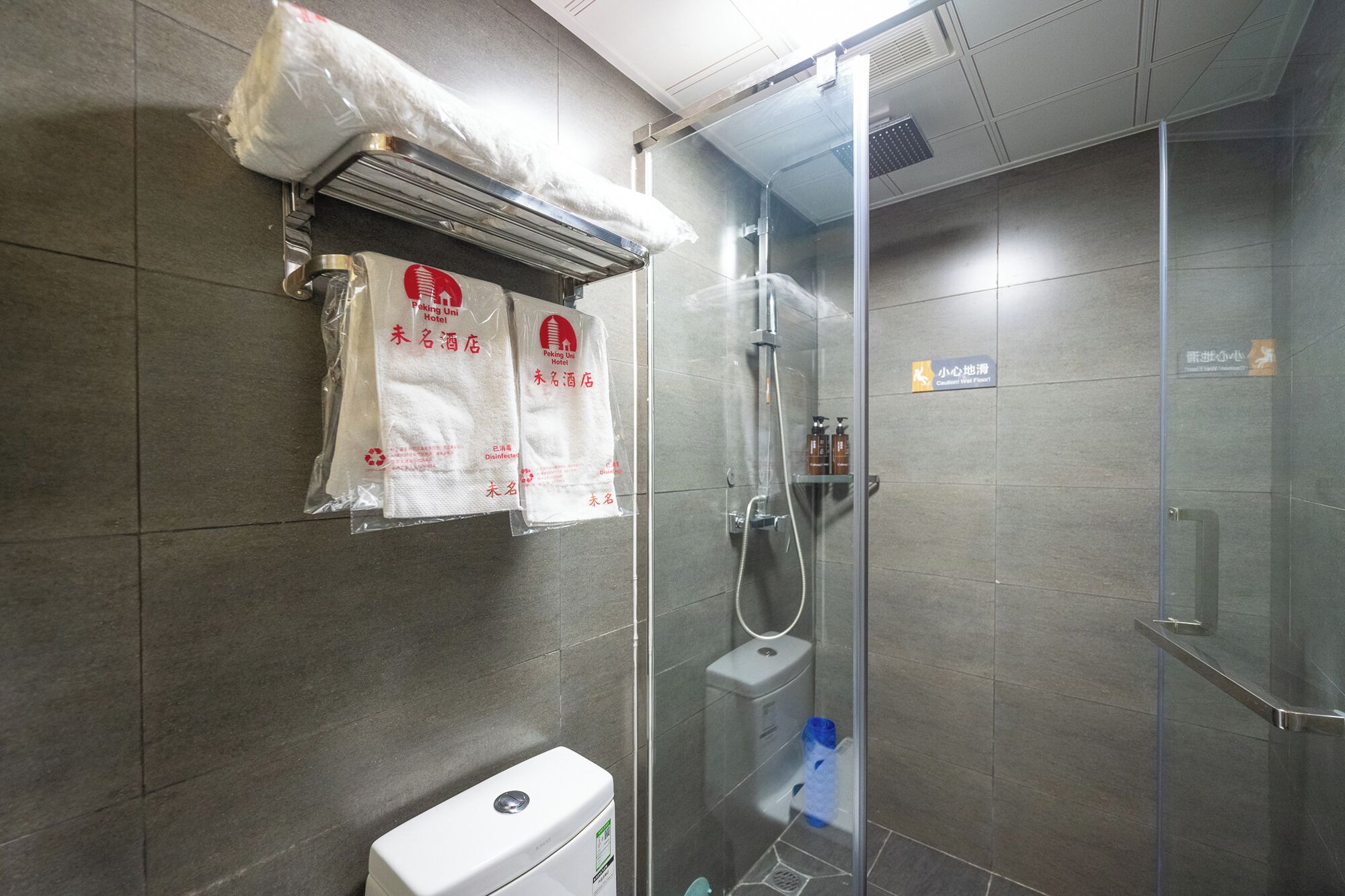 Ein modernes Badezimmer mit einer Duschkabine, einer Toilette und einem Handtuchhalter mit Handtüchern.