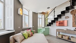 A modern hotel room with a large bed, a staircase, and a TV on the wall. - GuestReady - AMMA Braga - 10 (Braga)