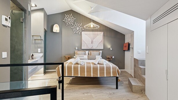 A modern bedroom with a large bed, a skylight, a shower, and a view of the city. - GuestReady - AMMA Braga - 10 (Braga)