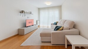 A modern living room with a sofa, a TV, and a white table. - GuestReady - Modern apartment in Boavista (Boavista)