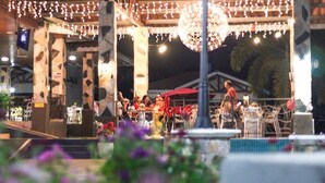 An outdoor dining area with tables and chairs, string lights, and a fountain. - Country Hills Las Lajas (San Felix)