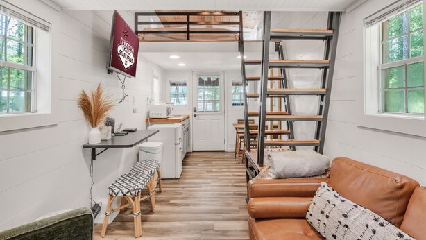 A compact living space with a kitchenette, a loft bed, a sofa, and a dining area.