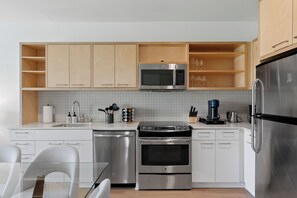 Een moderne keuken met witte kasten, roestvrijstalen apparatuur en een glazen eettafel.