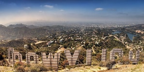 Une vue panoramique d’une ville, avec une colline imposante au premier plan et une étendue d’eau à l’horizon.