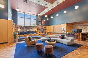A modern hotel lobby with a staircase, seating area, and a reception desk.