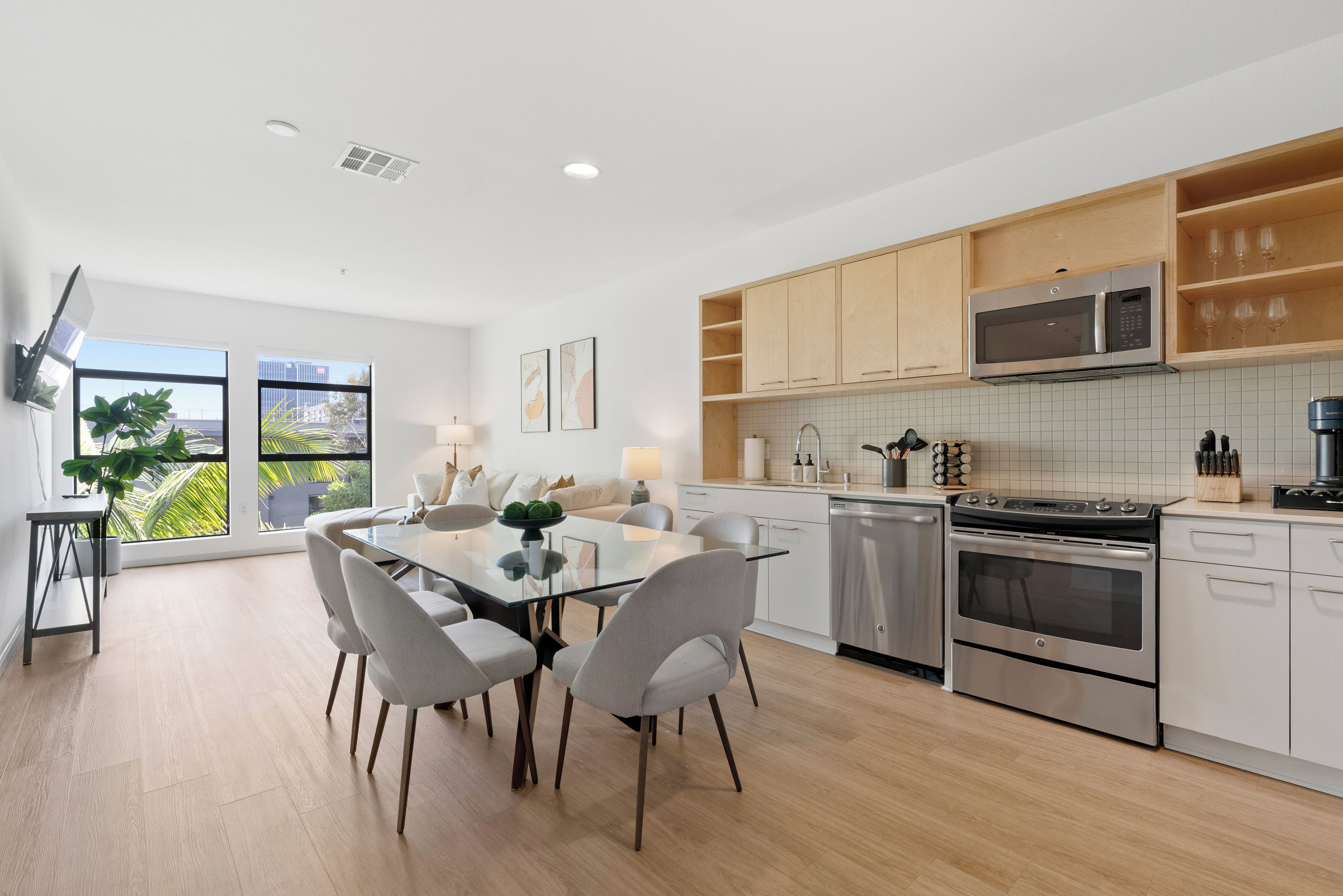 A modern kitchen with white cabinets, stainless steel appliances, and a dining area with a glass table and chairs.