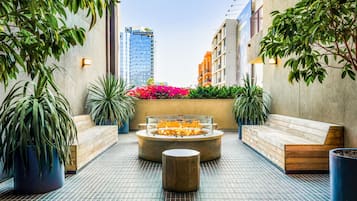 Eine Dachterrasse mit Feuerstelle, Sitzbereichen und Topfpflanzen.