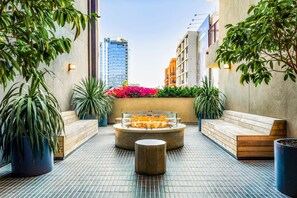 A rooftop terrace with a fire pit, seating areas, and potted plants.