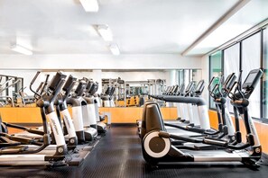 Een sportschool met meerdere loopbanden en fitnessapparaten, grote ramen en een lichte inrichting.