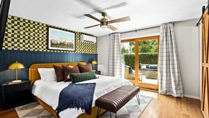 A bedroom with a bed, a ceiling fan, a window with curtains, a checkered wall, and a picture on the wall. - Boutique UO Stay • Epic Game Room • Walk to Autzen (Eugene)