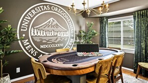 A conference room with a round table, chairs, a laptop, and a logo on the wall. - Boutique UO Stay • Epic Game Room • Walk to Autzen (Eugene)