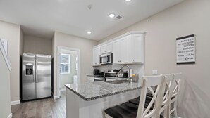 A modern kitchen with white cabinets, stainless steel appliances, and a granite countertop. - Branson Fun Zone | Dog-Friendly • Games • Pool (Branson)