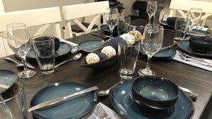 A dining table set with blue plates, clear glasses, and silverware. - Branson Fun Zone | Dog-Friendly • Games • Pool (Branson)