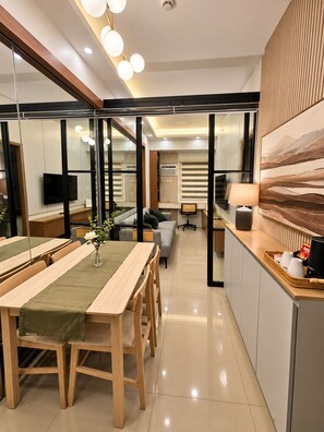 A modern kitchen with a dining area, a sofa, and a TV.