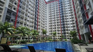 Un edificio residencial alto con piscina y sillas de descanso.