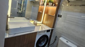 Un baño compacto con lavamanos integrado, inodoro y lavadora.