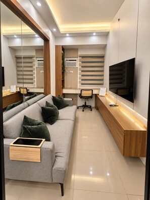 Un salon moderne avec un canapé, un bureau, une télévision et un miroir.