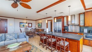 Una cocina moderna con una isla central, armarios de madera, electrodomésticos de acero inoxidable y un comedor con sofá y sillas.
