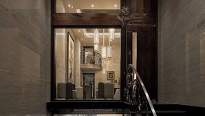 Un moderno vestíbulo de hotel con un mostrador de recepción de madera, una escalera y un candelabro.