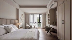Un dormitorio moderno con una cama grande, un escritorio y una silla. Se ve un paisaje al aire libre a través de la ventana.