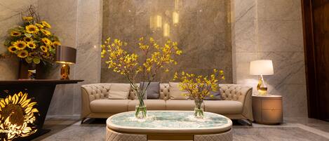 A lobby with a round coffee table, a sofa, and a lamp.