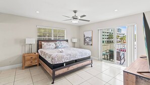 A bedroom with a bed, bedside tables, a ceiling fan, and a view of the outside balcony. - Beach, Pool; Las Olas Getaway (Fort Lauderdale)