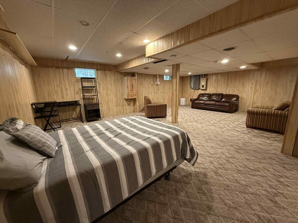 Une chambre avec un lit, un bureau, une chaise, un canapé et un téléviseur.