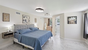 A bedroom with a bed, nightstands, a ceiling light, and artwork on the walls.