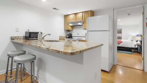 A modern kitchen with a granite countertop, stainless steel appliances, and wooden cabinets.