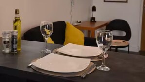 Ett matbord dukat med tallrikar, bestick och glas, med en flaska och behållare för kryddor och såser på sidan.