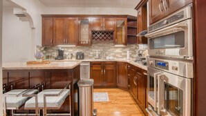 Una cocina moderna con armarios de madera, electrodomésticos de acero inoxidable y un refrigerador de vinos empotrado.