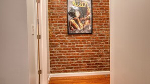 Un pasillo con pared de ladrillo y una obra de arte enmarcada que muestra una figura con corona.