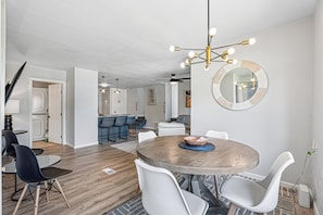 Un espace repas moderne avec une table ronde, des chaises blanches et un plancher en bois.