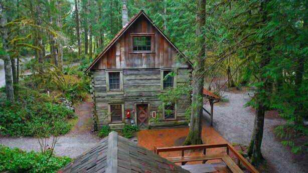 A rustic cabin with a wooden exterior, a front porch, and a chimney.