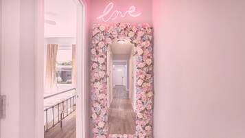 A hallway with a floral mirror and neon 'love' sign.