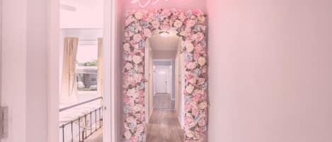 A hallway with a floral mirror and neon 'love' sign.