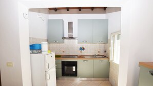 A compact kitchen with light blue cabinets, a white refrigerator, and a small oven.