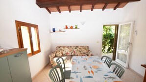 A dining area with a table set for four, a sofa, and a kitchen counter.
