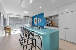 Une cuisine moderne dotée d’un îlot central, de tabourets de bar et offrant une vue sur l’extérieur.