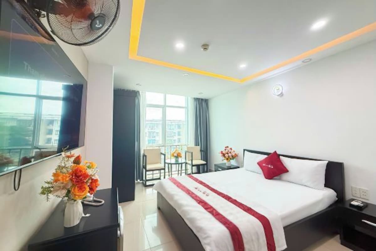 Quarto de hotel com uma cama, mesa de cabeceira e televisão.