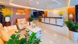 A hotel lobby with a reception desk, leather sofas, a coffee table, and potted plants. - Bien Sao Hotel Duong Quang Ham (Ho Chi Minh City)